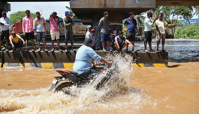 A motorist wades through a street after heavy monsoon rains in Bangalore on September 5, 2022. — AFP