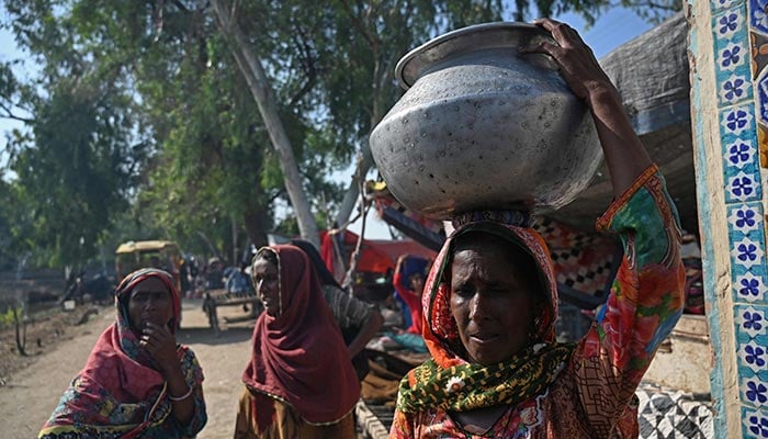Internally displaced flood-affected women carry water pots at a makeshift camp in Mehar city after heavy monsoon rains in Dadu district, Sindh province on September 9, 2022. — AFP/File