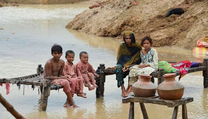 A mother is seen sitting along with her children in flood-battered setting in Balochistan. APP