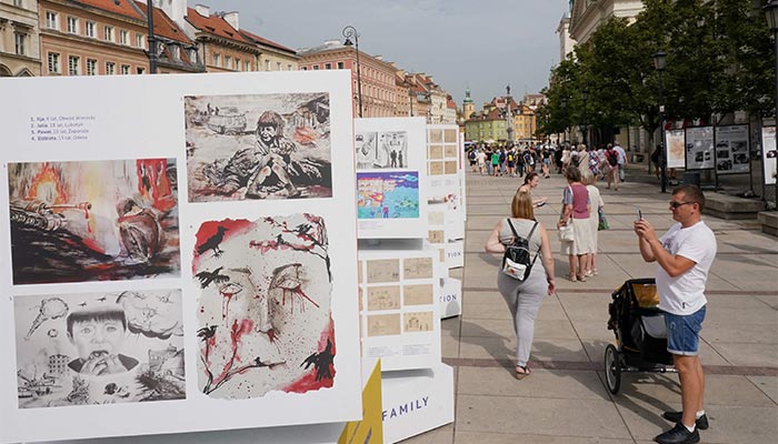 A man takes pictures of children´s drawings of war that are part of the Mom, I don´t want war! open air exhibition on display in Warsaw, Poland, on August 24, 2022. — AFP/File