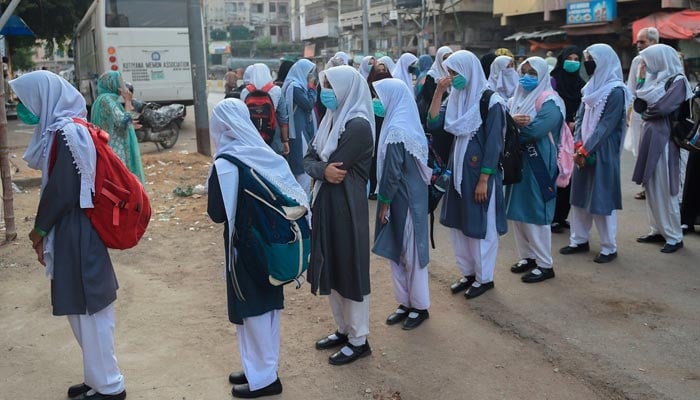 Students in Karachi stand in queue waiting to enter their school.