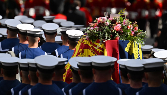 Royal Navy Sailors walk ahead and behind the coffin of Queen Elizabeth II, draped in the Royal Standard, as it travels on the State Gun Carriage of the Royal Navy from Westminster Abbey to Wellington Arch in London- AFP