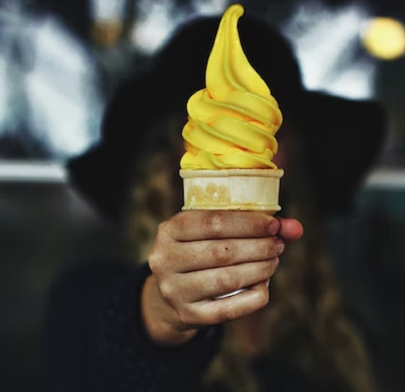 Woman holding banana flavoured ice cream cone.— Unsplash