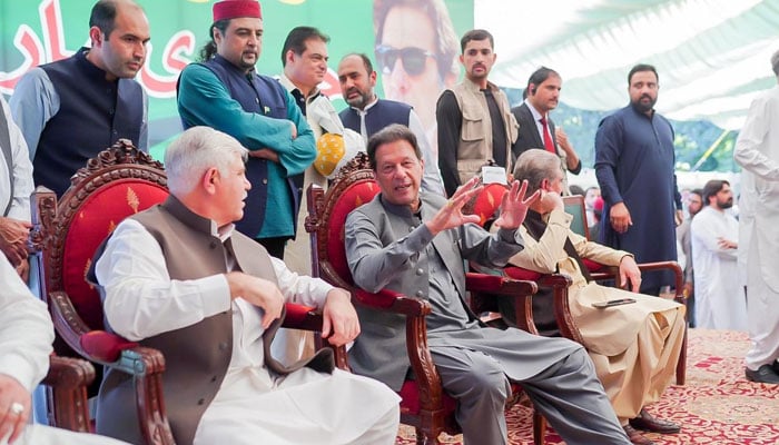 Ex-PM Imran Khan sitting on stage before addressing the party workers in Peshawar on October 4, 2022. Twitter/ShibliFaraz