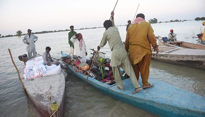 Internally displaced people use a boat to cross the flooded area in Dadu district, Sindh province on September 27, 2022. — AFP/File