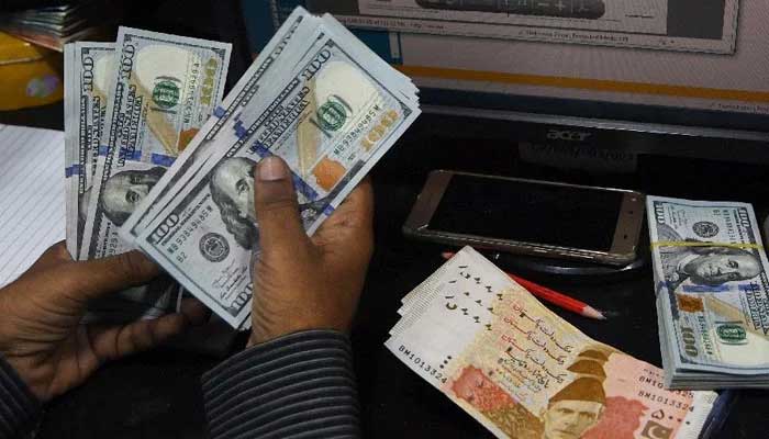 A currency dealer counts US dollars at a shop. — AFP/File