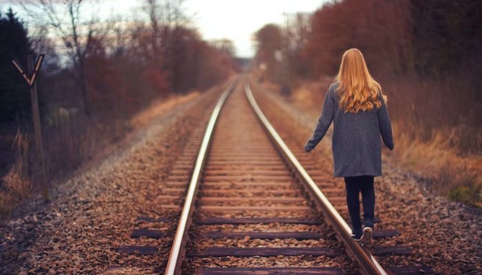 A woman walking on the edge of a railtrack. —  Unsplash