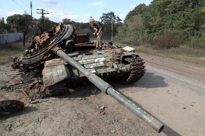 A girl inspects a destroyed Russian tank near the village of Oskol, Kharkiv region. AFP