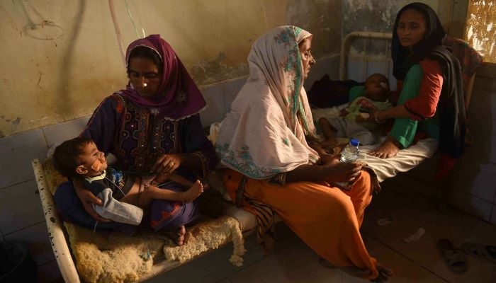 Women take care of their sick children at a makeshift medical camp set for people displaced by floods in Dadu district, Sindh province on September 27. — AFP