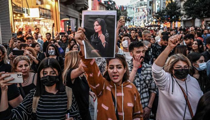 People protest after Mahsa Aminis death, raising slogans and holding her photo.— AFP