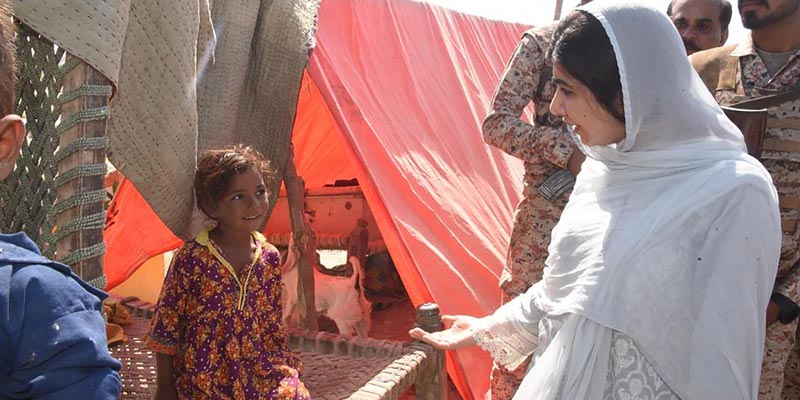 This handout picture taken and released by Chief Minister House Office of Sindh Province on October 12, 2022 shows Nobel Peace laureate Malala Yousafzai (R) meeting with flood-affected families at a makeshift camp in Johi, Dadu district of Sindh province. — AFP