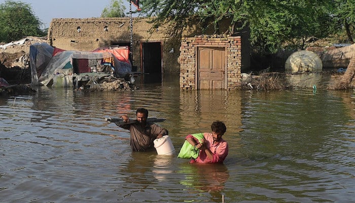 Flood affected people carry belongings out from their flooded home in Shikarpur, Sindh province, on August 31, 2022. - AFP