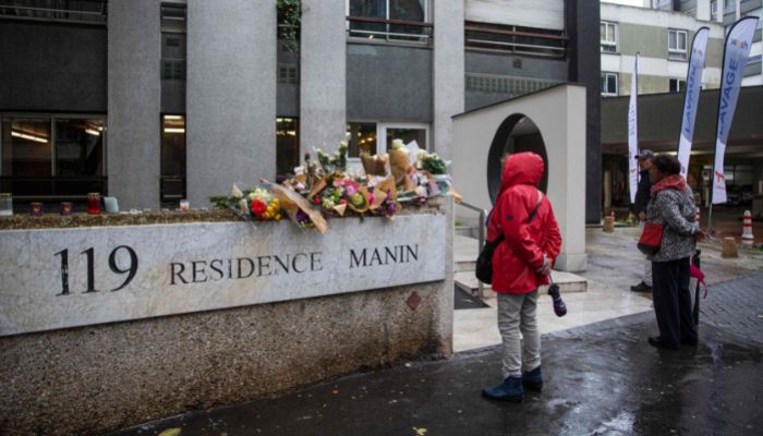 Members of the public stand in front of bunches of flowers displayed outside the building in Paris on October 17, 2022, where lived a 12-year-old schoolgirl, named Lola, three days after her body was discovered in a trunk in the 19th district.— AFP