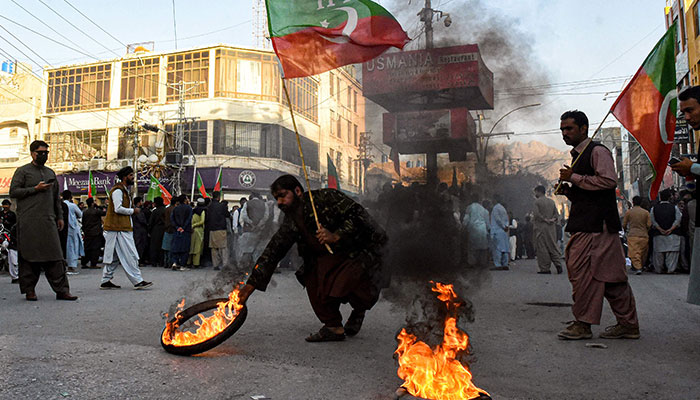 Activists of Pakistan Tehreek-e-Insaf (PTI) party burn tyres during a protest against the disqualifying decision of former prime minister Imran Khan on a street in Quetta on October 21, 2022. — AFP