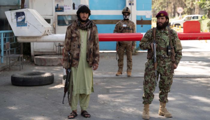 Taliban men stand guard as students sit for their university entrance exams, at an entrance gate of Kabul university in Kabul on October 13, 2022.— AFP