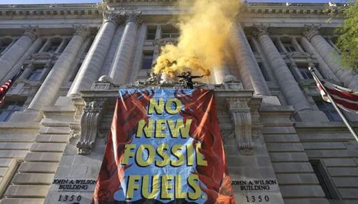 Un attivista ambientale con il gruppo Extinction Rebellion DC scala il Wilson Building come parte di una manifestazione per la Giornata della Terra contro i combustibili fossili a Washington, DC il 22 aprile 2022.  — AFP