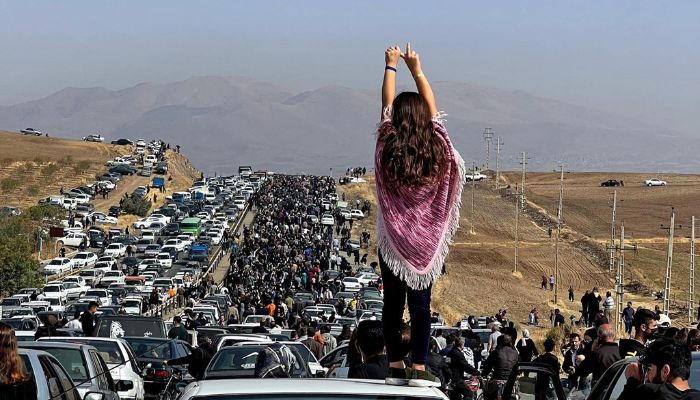 This UGC image posted on Twitter reportedly on October 26, 2022 shows an unveiled woman standing on top of a vehicle as thousands make their way towards Aichi cemetery in Saqez, Mahsa Amini´s home town in the western Iranian province of Kurdistan, to mark 40 days since her death.— AFP
