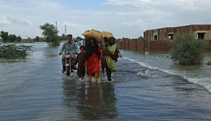 Stranded people wade through a flooded area after heavy monsoon rainfall in Rajanpur district of Punjab province on August 25, 2022. — AFP/File