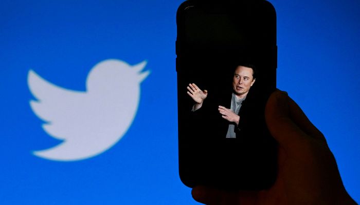 In this file illustration photo taken on October 4, 2022, a phone screen shows an image of Elon Musk with the Twitter logo visible in the background in Washington, D.C.  - France Press agency