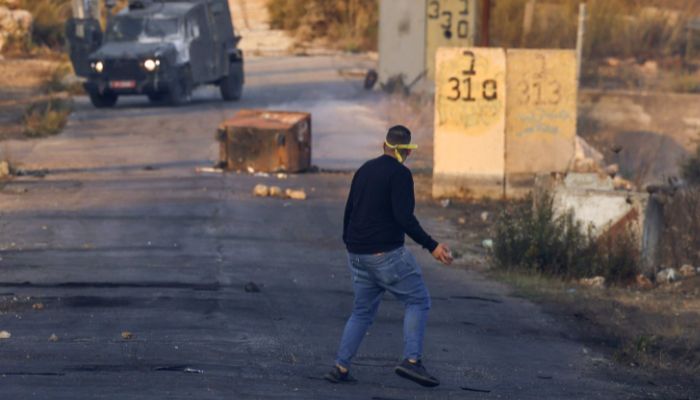 A Palestinian protester hurls rocks during clashes with Israeli security forces at the northern entrance to the city of Ramallah, near the Israeli settlement of Beit El in the occupied West Bank, after a demonstration by students from Birzeit University on November 5, 2022.— AFP