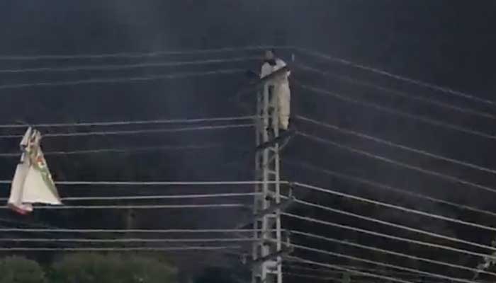 Screengrab from a video of the PTI worker climbing up an electric pole on Rawalpindis Murree Road, on November 7, 2022. — Twitter