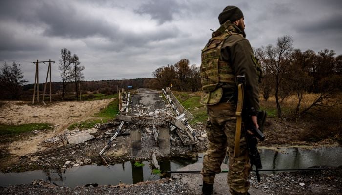 A Ukrainian soldier by a destroyed bridge near the Ukrainian border with Russia in the Kharkiv region.— AFP