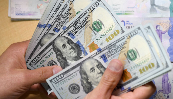 A man counts one hundred US dollar bills in Bogota, on October 24, 2022. — AFP/File