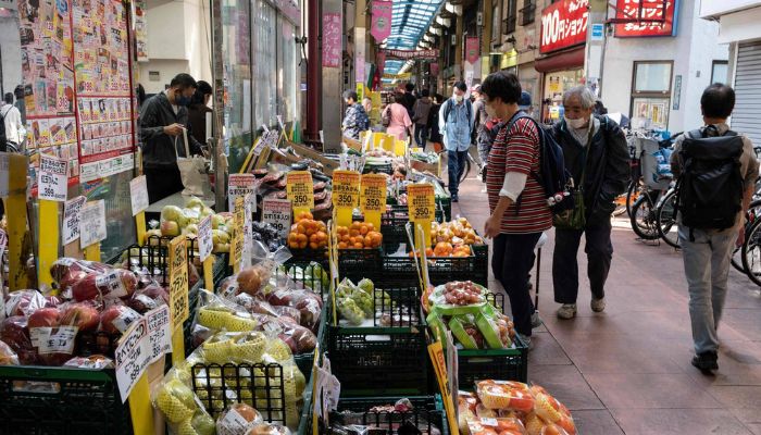 İnsanlar Tokyo'da bir süpermarketin önünde meyve ve sebzelere bakıyor.— AFP