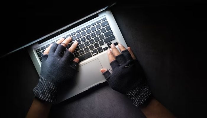 Hacker hand stealing data from laptop top down.— Unsplash