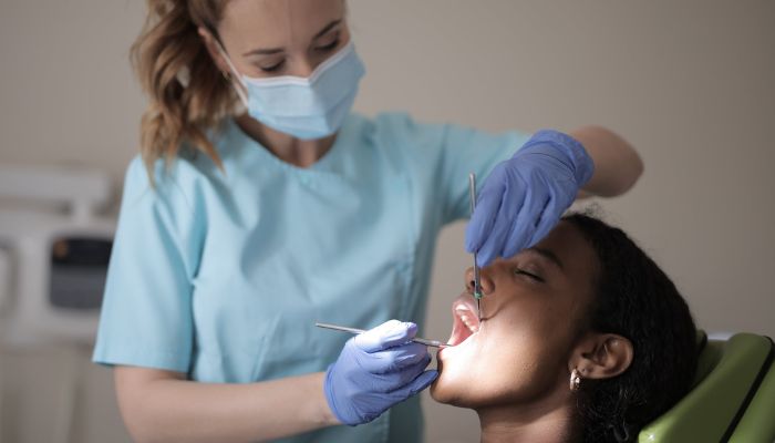Young female dentist treating teeth of female patient in modern clinic.— Pexels