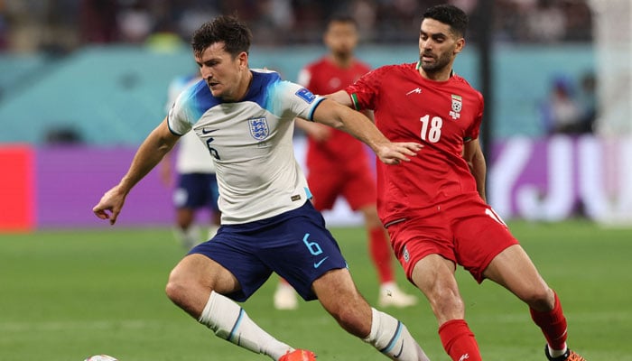 Englands defender #06 Harry Maguire(L) fights for the ball with Iran´s midfielder #18 Ali Karimi during the Qatar 2022 World Cup Group B football match between England and Iran at the Khalifa International Stadium in Doha on November 21, 2022. — AFP