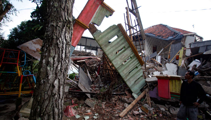 21 Kasım 2022'de Cianjur'da meydana gelen depremin ardından bir adam hasarlı evlerin yanında duruyor. — AFP