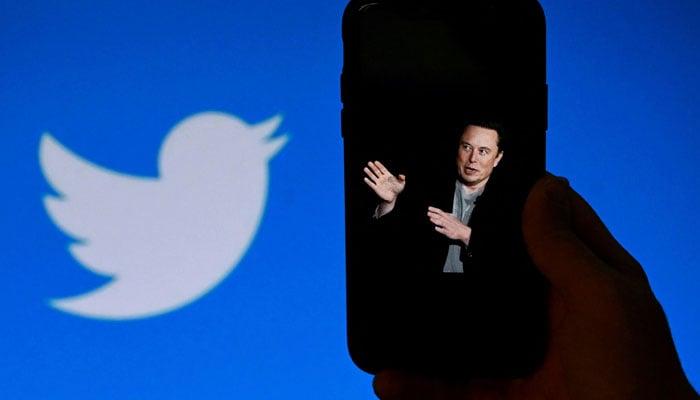 In this file photo taken on Oct. 4, 2022, a phone screen shows an image of Elon Musk with the Twitter logo visible in the background, in Washington, DC.  - France Press agency