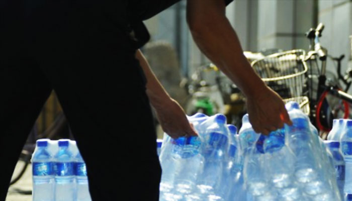A representational image showing a person carrying bottled water. — AFP/File