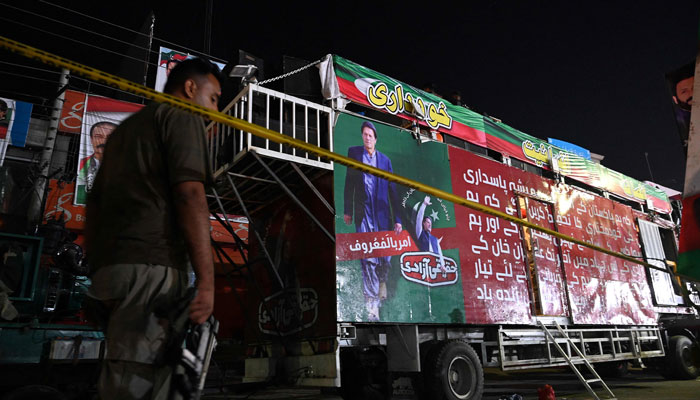 A police officer stands guard in front of a container truck used by the former Pakistani prime minister Imran Khan during his political rallies, hours after a gun attack in Wazirabad on November 3, 2022. — AFP/File