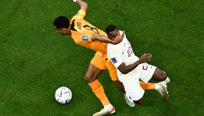 Qatar’s midfielder #23 Assim Madibo (R) is tackled by Netherlands´ forward #08 Cody Gakpo during the Qatar 2022 World Cup Group A football match between the Netherlands and Qatar at the Al-Bayt Stadium in Al Khor, north of Doha on November 29, 2022. — AFP