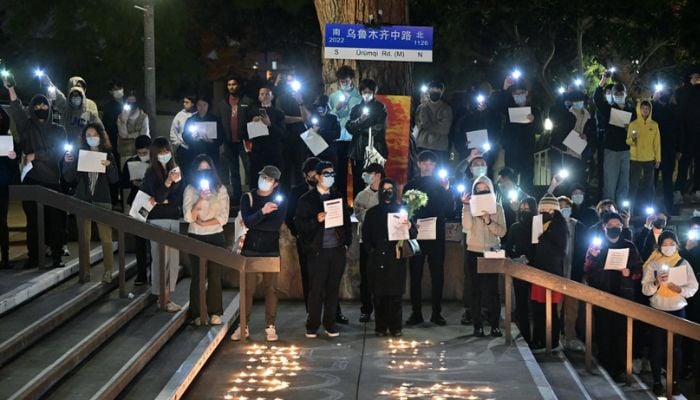 Standing beside a makeshift Urumuqi Road sign, people hold blank sheets of paper while protesting the deaths caused by an apartment complex fire in Urumqi, Xinjiang, China, at the Langson Library on the campus of the University of California, Irvine, in Irvine, California, on November 29, 2022.— AFP