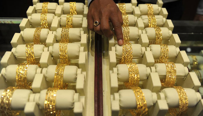 A sales assistant arranges gold bangles in a jewellery shop. — AFP/File