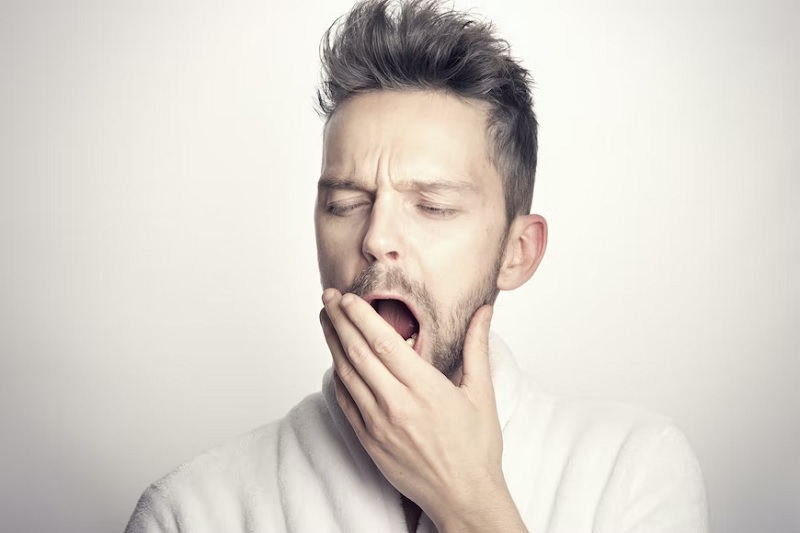 A sleep-deprived man yawning.— Unsplash