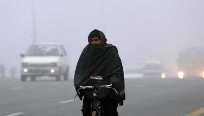 Representational image shows a man wrapped in shawl cycles on a road in Pakistan in cold weather. — AFP/File