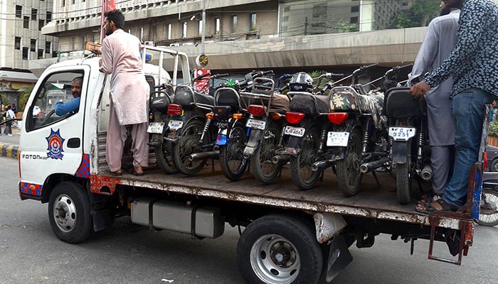 Traffic police carrying motorbikes from no parking area in Karachi on May 21, 2022. — INP
