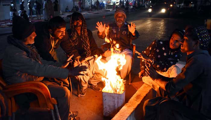 People warm their hands on bonfire to save themselves from cold waves during winter season in Karachi on Tuesday,  — PPI/File