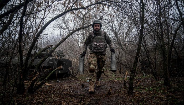 24. tugaydan Ukraynalı bir topçu, 10 Aralık 2022'de Rusya'nın Ukrayna'yı işgalinin ortasında, Donetsk bölgesi, Bakhmut yakınlarındaki cephe hattı boyunca bir pozisyonda boş topçu kovanları taşıyor.— AFP