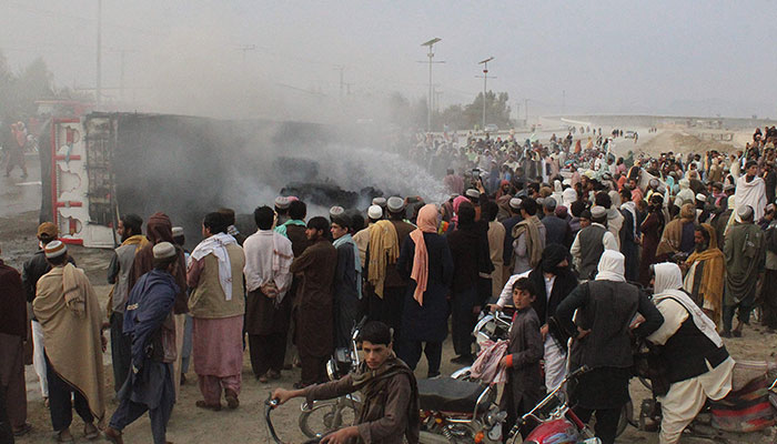 Residents gather around a burning truck after Taliban forces fired mortars at Pakistan´s border town of Chaman on December 11, 2022. — AFP