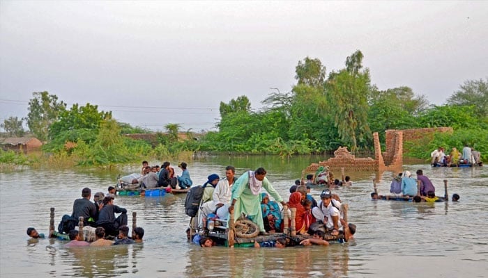 Internally displaced people wade through floodwaters after heavy monsoon rains in Jaffarabad district in Balochistan province on September 8, 2022. — AFP