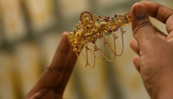A customer holds gold jewellery at a jewellery showroom on May 3, 2022. — AFP/File