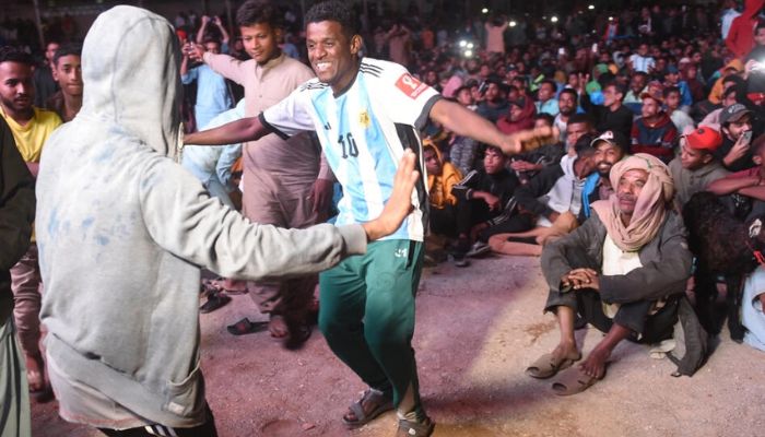 Pakistanlı futbol taraftarları, Karaçi'nin Lyari semtinde Arjantin ile Hırvatistan arasında oynanacak Dünya Kupası yarı finalinin canlı yayınını izlerken dans ediyor.— AFP