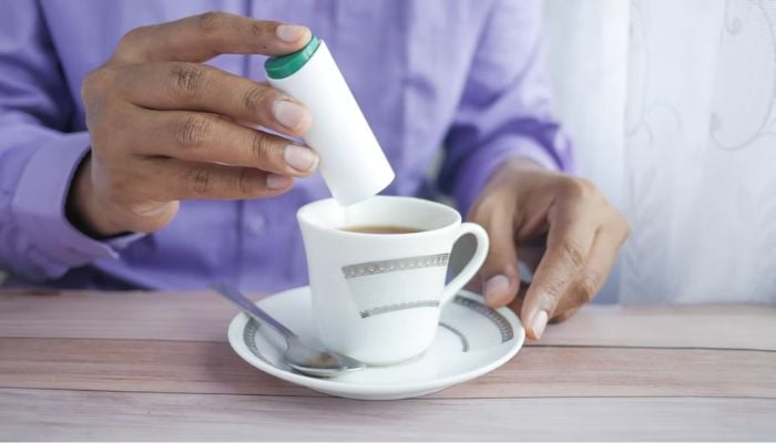 A person adding artificial sweetener to tea.— Unsplash