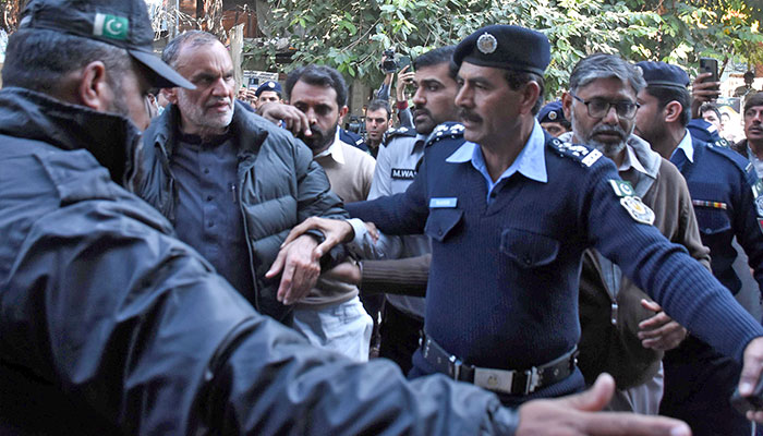 Police personnel escort PTI Senator Azam Khan Swati during his court hearing in controversial tweets case. — Online