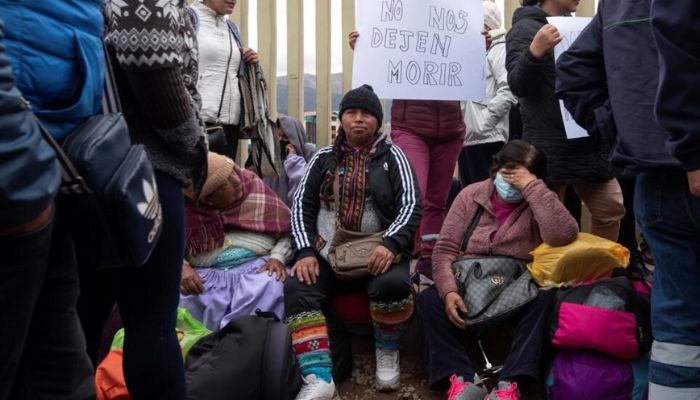 Passengers sit outside the entrance to the Alejandro Velasco Astete International Airport, in Cusco, Peru, on December 16, 2022.— AFP